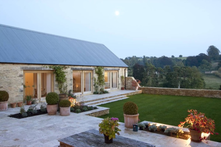 Vale Farm Cotswold stone barn exterior at dusk with terraced garden and countryside views
